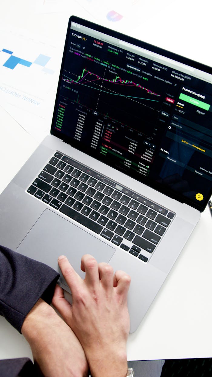 Professional Analyzing Stock Market Graphs On A Laptop, Showcasing Investment Insights.